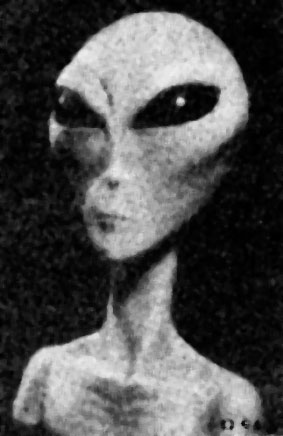 Grey alien extraterrestrial in dark black room, looking at viewer